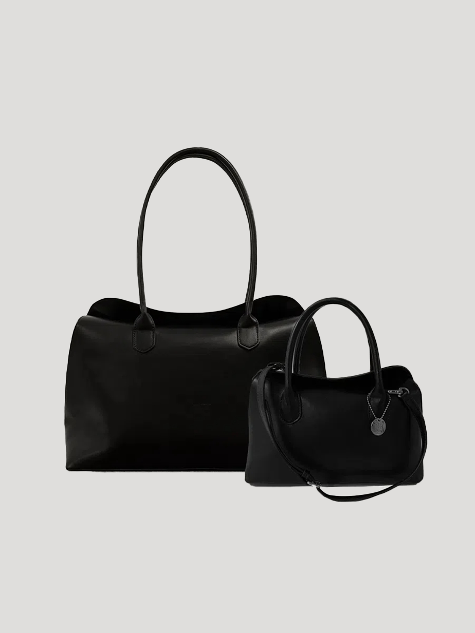 Two black leather handbags: a spacious top-handle design and a compact bag with a shoulder strap, on a light gray background.