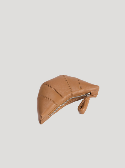 A croissant-shaped brown leather purse lies flat on a white background.