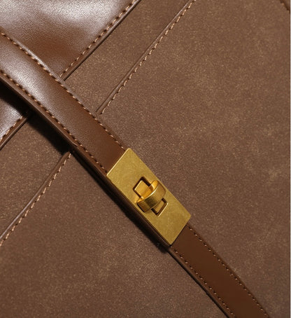 A close-up view of the golden metal lock on a brown work tote bag, featuring high-quality metal and excellent craftsmanship.