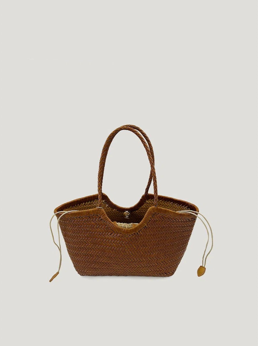 A brown woven leather tote bag with a spacious top-handle design and a nested bag, set against a clean white background, showcasing its elegant and functional features.