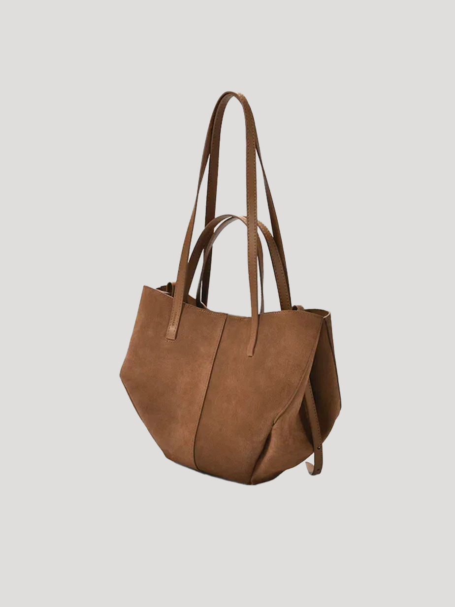 A front-side view of a brown hand/shoulder Polène bag, featuring suede leather and catfish whiskers, set against a white background.