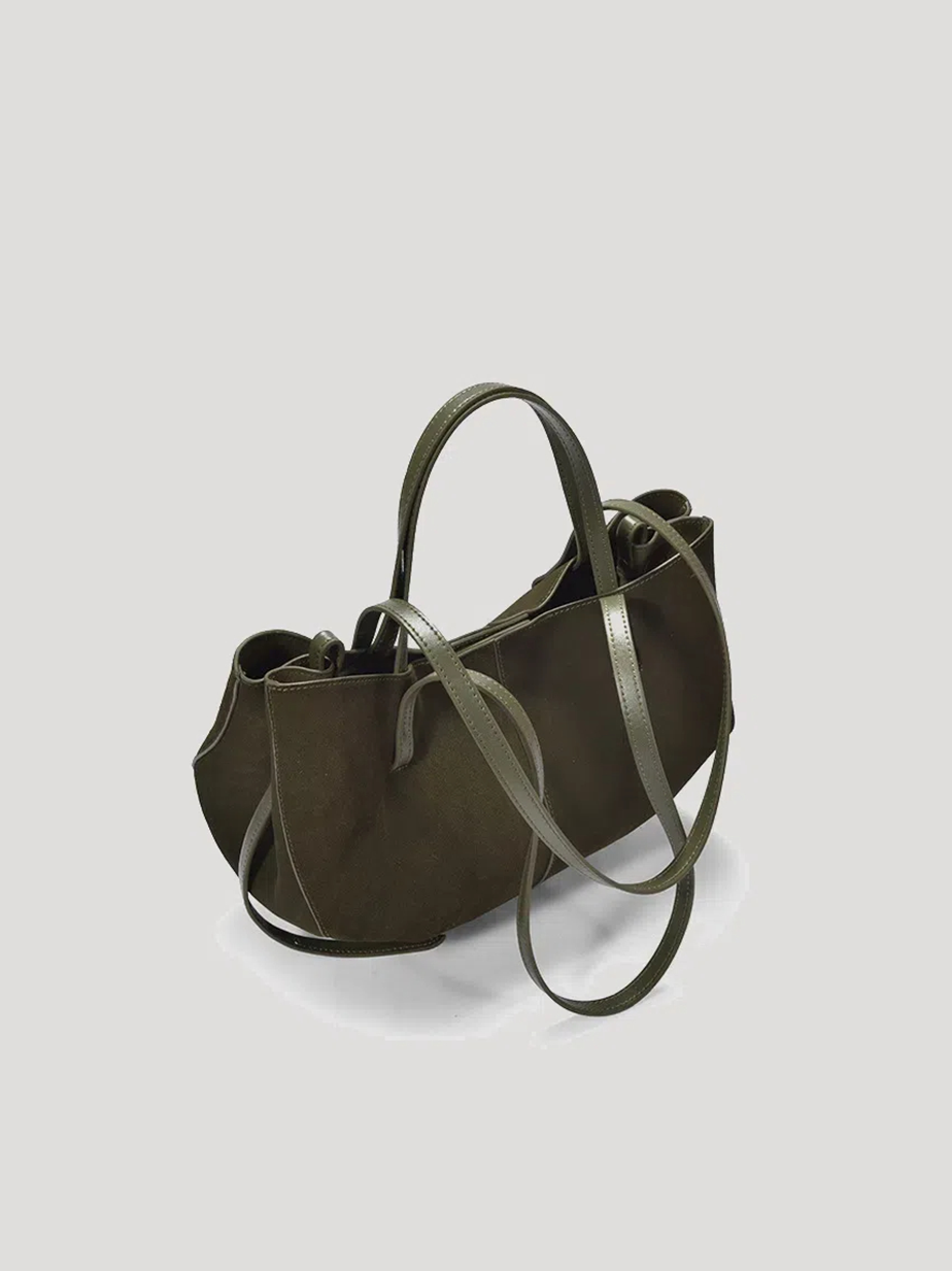 A front-side view of a green hand/shoulder Polène bag, featuring suede leather and catfish whiskers, set against a white background.