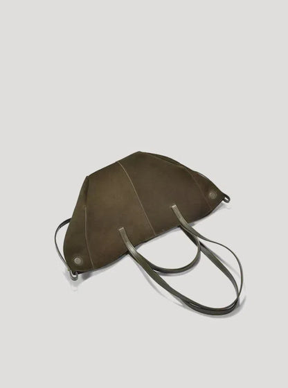 A green hand/shoulder Polene bag, featuring suede leather and catfish whiskers, with both long and short top handles, lies flat on a white background.